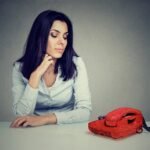 Засмучена жінка чекає дзвінка після першого побачення