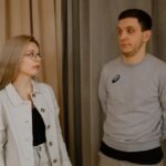 Сумна жінка сидить поруч із байдужим чоловіком у кімнаті